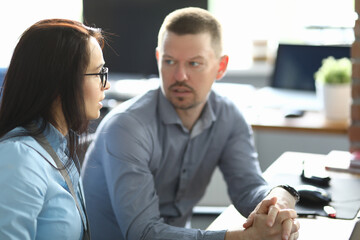 A man and a woman are sitting at a table in the office. Employees discuss work processes in the workplace