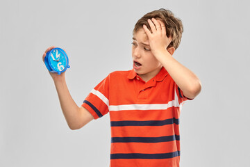 childhood, fashion and people concept - portrait of boy in red polo t-shirt with alarm clock over...