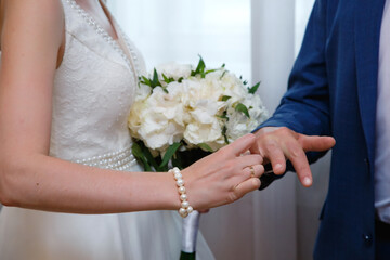 Close up of groom putting wedding ring on bride's finger. Bride and groom holding hands at wedding ceremony. Wedding rings on newlyweds hands.