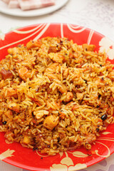 Eastern cuisine. Red plate with pilaf on the table. Sliced plate of brisket and sausage.