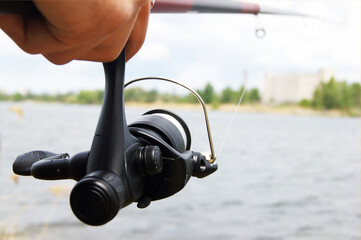 Wheel fishing rod closeup on a lake background.