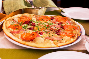Authentic pizza with tomatoes, smoked sausage, bacon and parsley. Morning atmospheric lighting, fashionable trendy spot soft focus. Preparation for design creative menu.