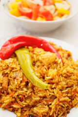 Eastern cuisine. Red plate with pilaf on the table. A plate with salad.