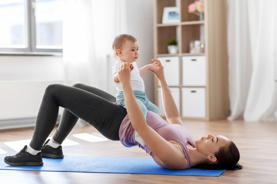 family, sport and motherhood concept - mother with little baby exercising at home