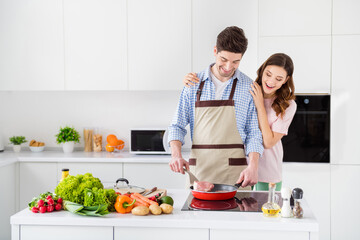 Portrait of two nice attractive careful glad positive cheerful cheery spouses making domestic homemade meal spending weekend in light white interior kitchen house apartment indoors