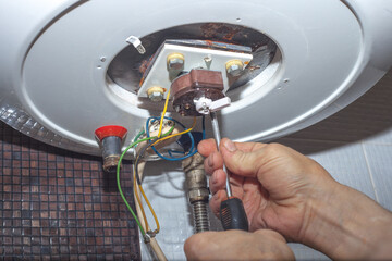 Repairman hand are fixing broken electric boiler