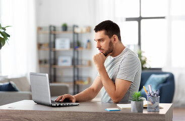 technology, remote job and business concept - man with laptop computer working at home office