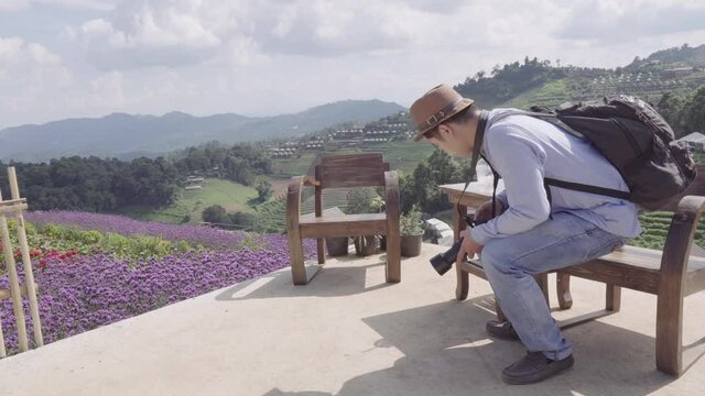 A young man drinking and taking pictures in the flower garden at Moncham, Chiang Mai, Thailand