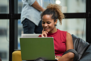 Young woman using laptop sitting on sofa. Young female designers working at modern office, girl...