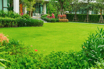 Huis in het park, Groen gazon, voortuin is prachtig aangelegde tuin, Bloemen in de tuin, Groen gras, Modern huis met mooi aangelegde voortuin, Gazon en tuin wazige achtergrond.