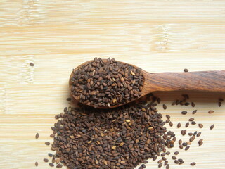 Brown color raw whole dried Sesame seeds on wooden spoon