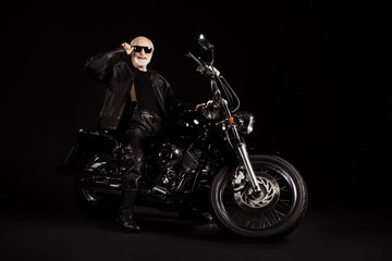Naklejka na ściany i meble Portrait of his he nice attractive content cheerful grey-haired guy dude hipster traveler sitting on chopper spending weekend holiday tour trip touching specs isolated black color background