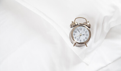Classic alarm clock on bed.