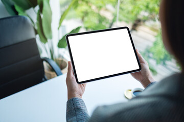 Mockup image of a woman holding tablet with blank white desktop screen in the office