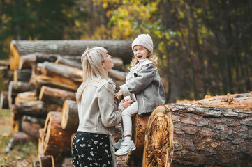 Little girl with his young mother during stroll in the forest.