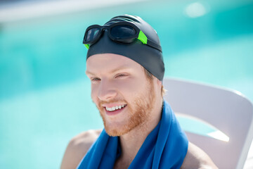 Closeup of joyful face man in swimming cap and goggles