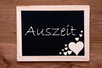 Balckboard With German Text Auszeit Means Downtime. Rustic Wooden Heart Decoration. Brown Wooden Background