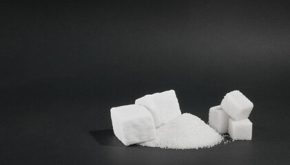 lump and granulated sugar on a black background, a source of glucose and sucrose, an additive to tea