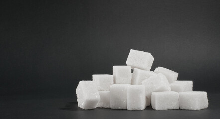 White cubes of sugar on a black background. source of glucose. A sweet addition to tea.