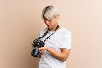 Young asian man over isolated background with a professional camera