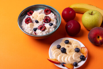 healthy breakfast concept with oat porridge and fruit on orange background