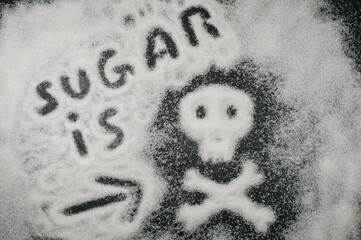 inscription from white granulated sugar on a black background, sugar is death. source of glucose...