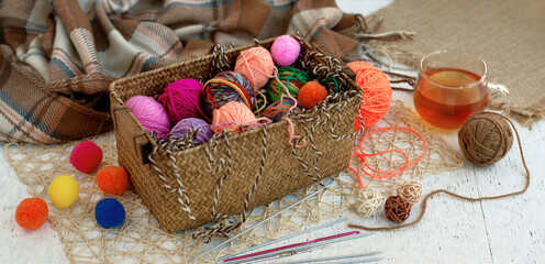 Knitting and yarn in panorama view. Multicolored balls of yarn in a basket for knitting clothes. Knitting is a kind of needlework and a hobby.