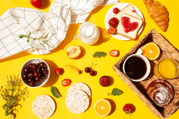 Morning breakfast with a cup of coffee, a basket with pastries and fruits on a yellow background