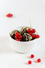 Chocolates with cinnamon and cardamom and red currants in a white bowl. Sugar, lactose, gluten free.
