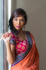 Young beautiful woman wearing Saree stainding by the window.