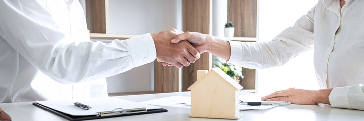 Estate agent and customer shaking hands after contract signing about home insurance