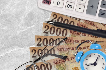 2000 Hungarian forint bills and calculator with glasses and pen. Business loan or tax payment...