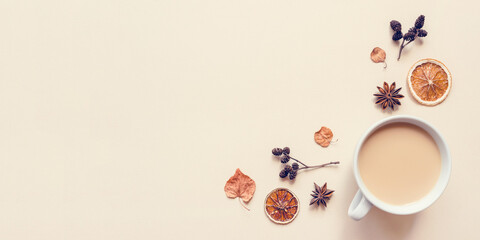 Autumn pastel background. A cup of hot coffee or tea with milk with autumn leaves and anise. Banner with copy space for text. Flat lay, top view.