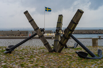 Fototapeta na wymiar Three old anchors at Parapeten in Helsingborg, Sweden. This area has a long and close relationship with maritime activity. Swedish flag in the background