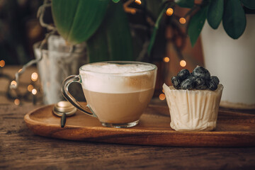 Coffee with milk in a transparent cup and a cake with berries. Breakfast in a cafe