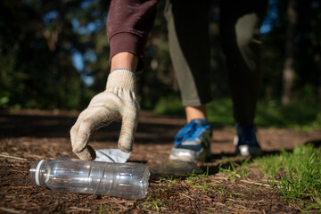 Woman collecting plastic garbage in forest