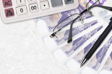 20 British pounds bills fan and calculator with glasses and pen. Business loan or tax payment...