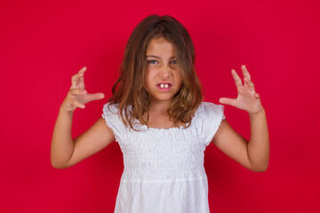 Little caucasian girl with blue eyes wearing white dress standing over isolated red background...