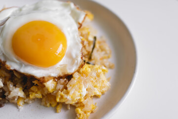 Homemade fried rice with fried egg on top served on white dish.