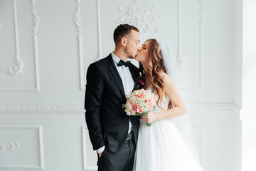 The first meeting of the groom in a black suit and the bride in a white wedding dress with a bouquet in the interior of a photo studio on a white and black background