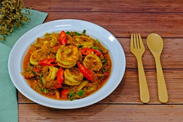 Stir fried shrimps with curry powder with spoon and fork on wooden table. Ready to serve. Thai Food.