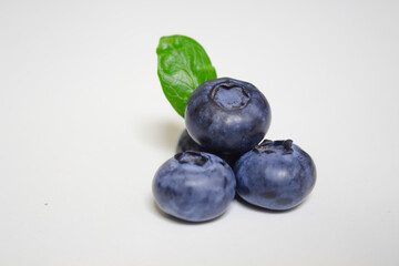 Fresh blueberries with green leaf isolated on white background. Close up, studio photography. Pile of blueberries macro shot. Healthy food and drinks. Vitamins. Seasonal berries.