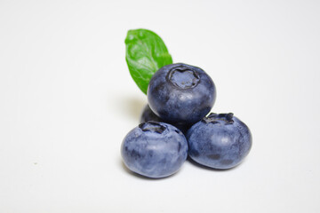 Fresh blueberries with green leaf isolated on white background. Close up, studio photography. Pile of blueberries macro shot. Healthy food and drinks. Vitamins. Seasonal berries.