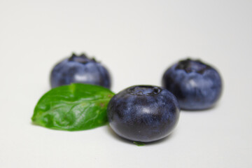 Fresh blueberries with green leaf isolated on white background. Close up, studio photography. Pile of blueberries macro shot. Healthy food and drinks. Vitamins. Seasonal berries.