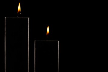 Burning black candle on dark