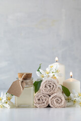 Jasmine essential oil, candles and towels, flowers on a white background. Spa and wellness concept. Copy space.