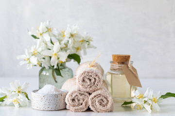 Obraz na płótnie Canvas Spa concept of jasmine oil, with bath salt and flowers on a white background. Spa and wellness still life. Copy space.