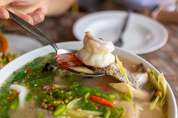 Thai spicy tom yam seafood served on white bowl in local restaurant.