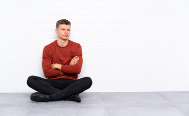 Obraz na płótnie Canvas Young handsome man sitting on the floor thinking an idea