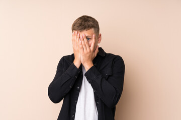 Young handsome man covering eyes and looking through fingers